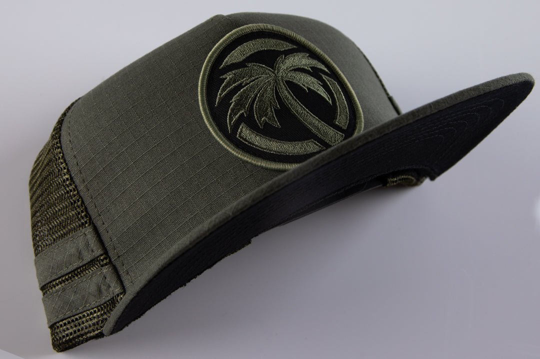 Front of Heat Wave Visual od green trucker hat with socom patch.
