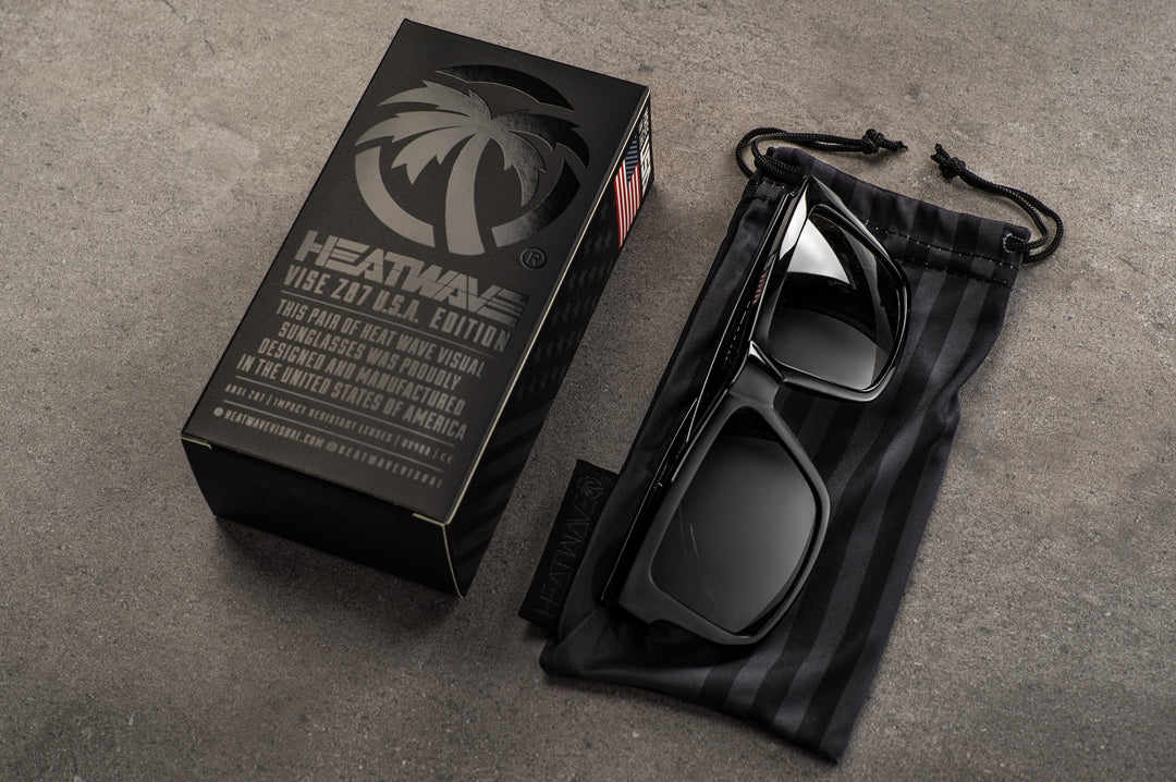 A pair Heat Wave Visual USA made Vise Sunglasses on top of a microfiber bag on a concrete ground.