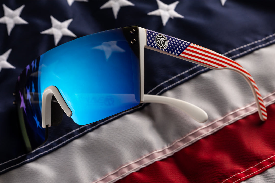 Heat Wave Visual Lazer Face Z87 Sunglasses with white frame, USA print arms and galaxy blue lens lying on a USA flag