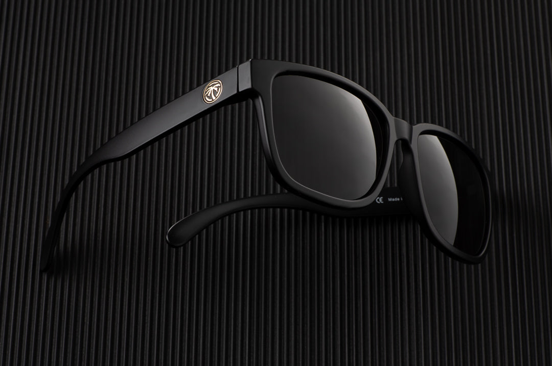 Laying on the table is the Heat Wave Visual Apollo Sunglasses with black frame, and black lenses.