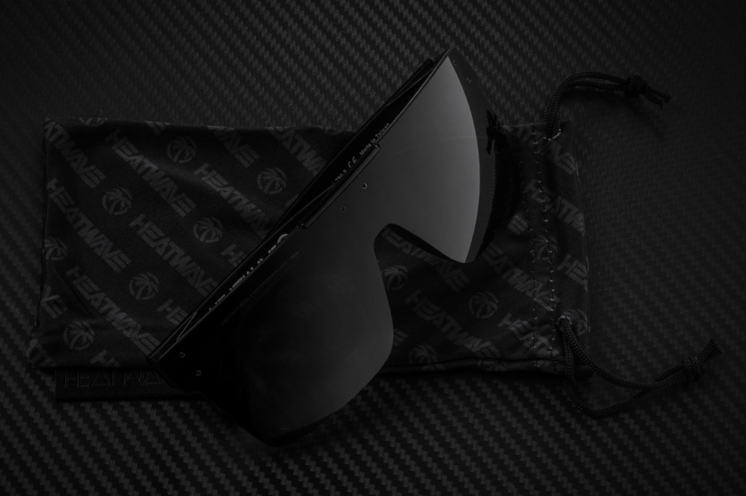 Heat Wave Visual Quatro Sunglasses with black frame, black bar and black lens lying on a microfiber.