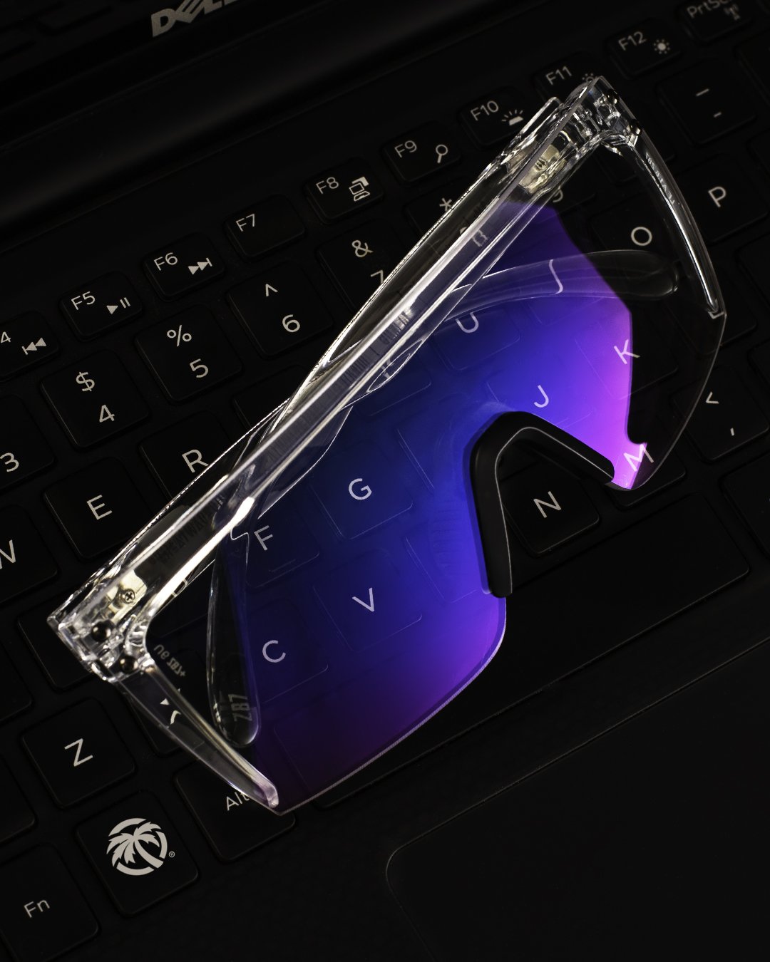 Heat Wave Visual Lazer Face Z87 Sunglasses with clear frame, black nose piece and clear blue blocker on top of a laptop keyboard. 