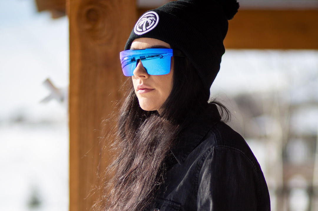 Young woman out in the snow wearing Heat Wave Visual Quatro Sunglasses with black frame and galaxy blue lens.