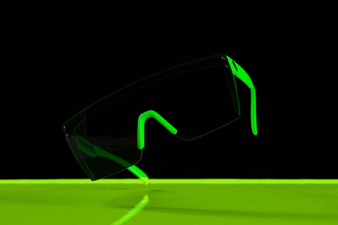 Heat Wave Visual Lazer Face Z87 Sunglasses with moto green frame and black lens hovering over green liquid.