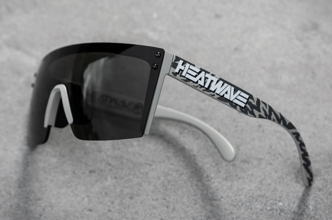 Side view of Heat Wave Visual Lazer Face Z87 Sunglasses with grey frame, hydroshock print arms and black lens on concrete ground.