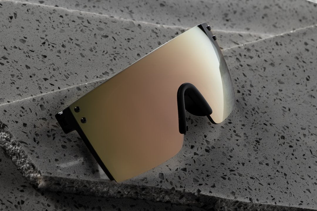 Heat Wave Visual Lazer Face Z87 Sunglasses with black frame and rose gold lens lying on granite slabs.