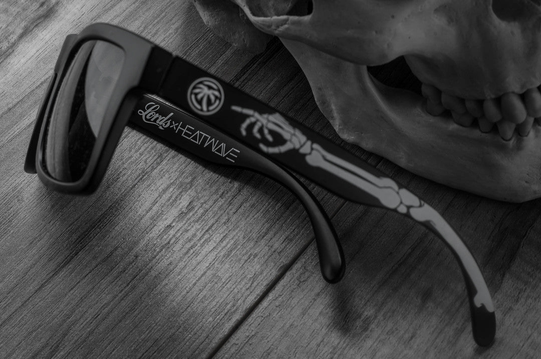 Close up side view of Heat Wave Visual Vise Sunglasses with black frame, bones print arms and black lenses.