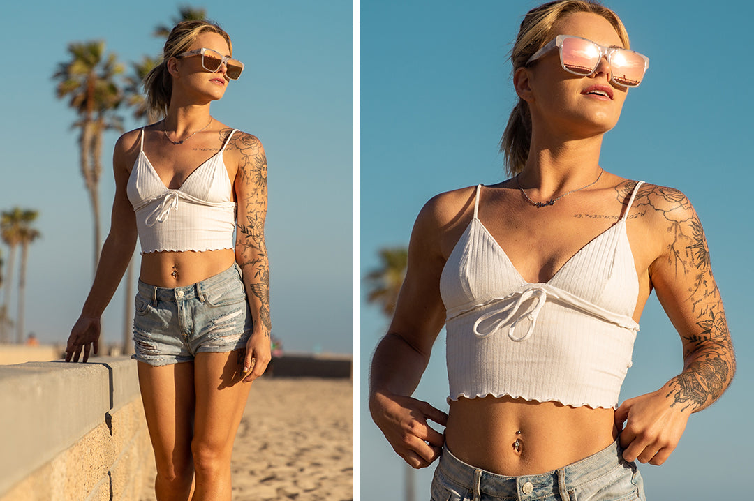 Young woman at the beach wearing Heat Wave Visual Womens Marylin Sunglasses with marble frame and rose gold lenses.