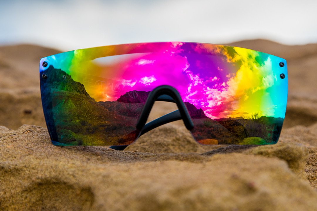 Heat Wave Visual Lazer Face Z87 Sunglasses with black frame and spectrum pink yellow lens on a rock overlooking some mountains.
