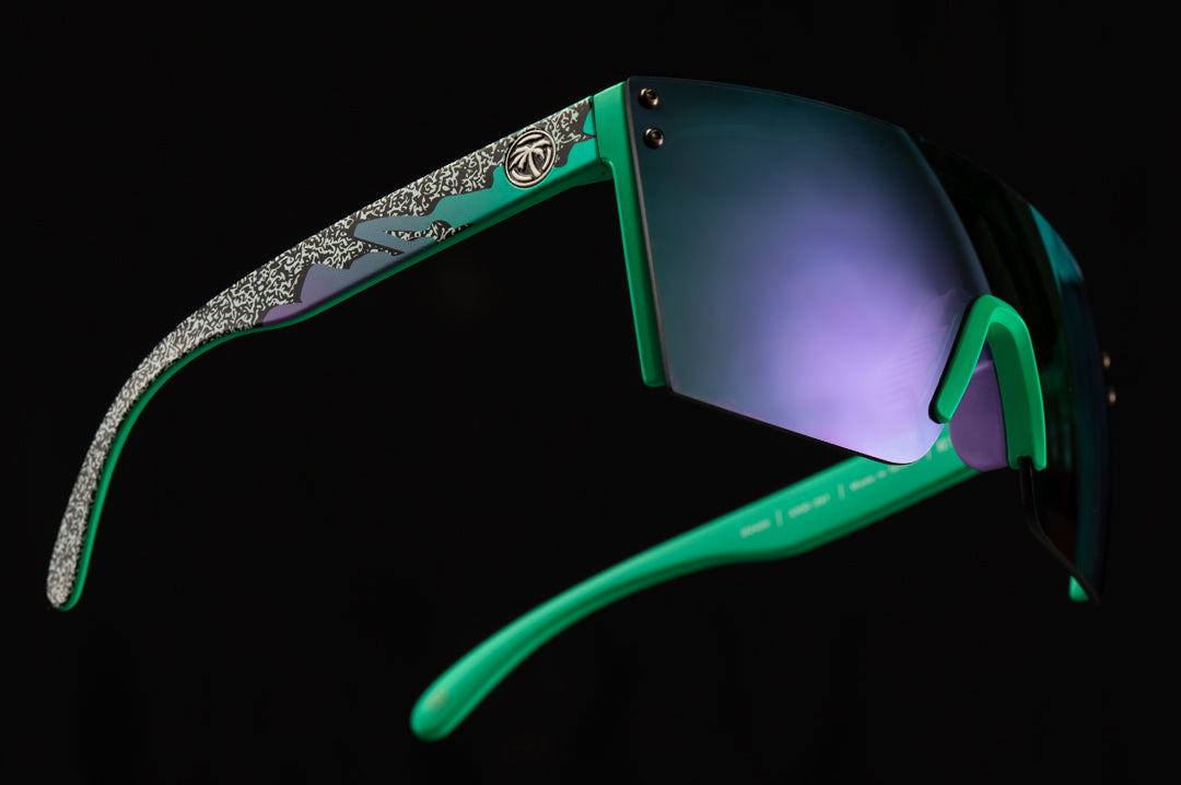 Side view of Heat Wave Visual Lazer Face Z87 Sunglasses with green frame, scribble print arms, ultra violet lens and black side shields floating in the air.