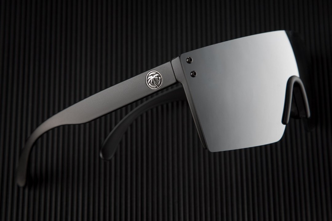 Side view of Heat Wave Visual Lazer Face Z87 Sunglasses with black frame and silver lens on black table.