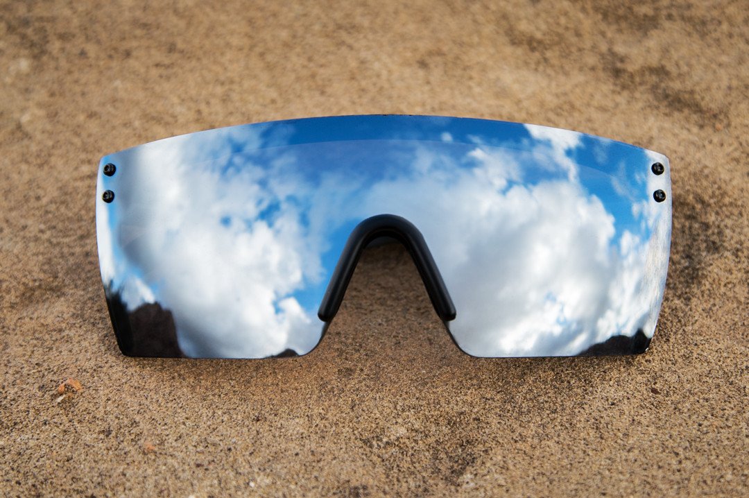Lying on sand is Heat Wave Visual Lazer Face Z87 Sunglasses with black frame and silver lens.