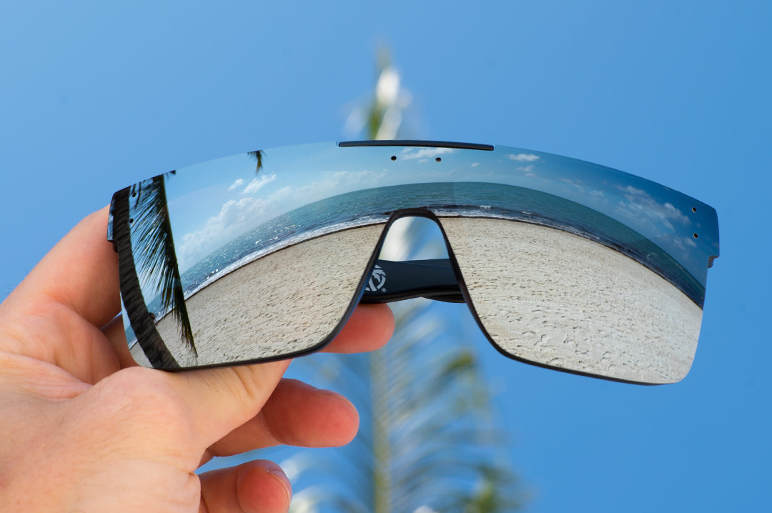 Heat Wave Visual Quatro Sunglasses with black frame and silver lens at the beach.