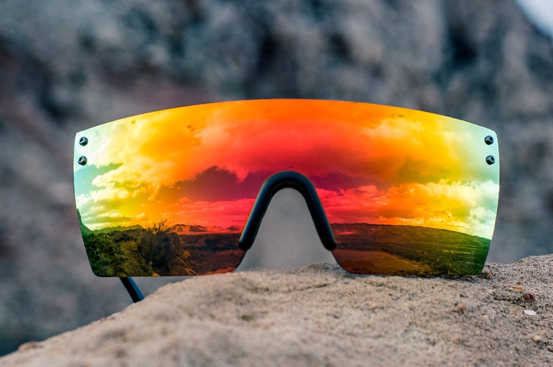 Heat Wave Visual Lazer Face Z87 Sunglasses with black frame and sunblast orange yellow lens on a rock overlooking the desert landscape.