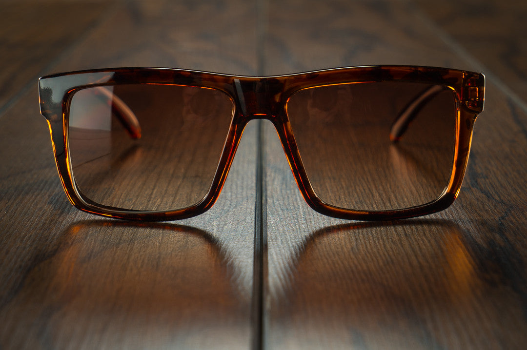 Front view of Heat Wave Visual Tortoise Vise sunglasses on wooden floor.