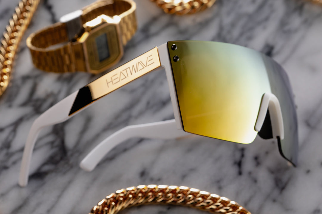 Heat Wave Visual Lazer Face Sunglasses with white frame, gold metal arms and gold lens surround by gold bling.