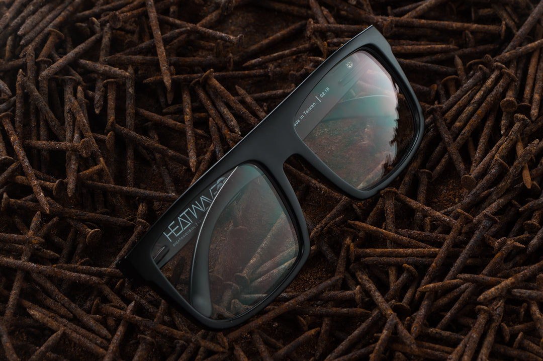 Front of Heat Wave Visual Z87 Regulator Sunglasses with black frame and clear lenses laying in a bed of rusty nails.